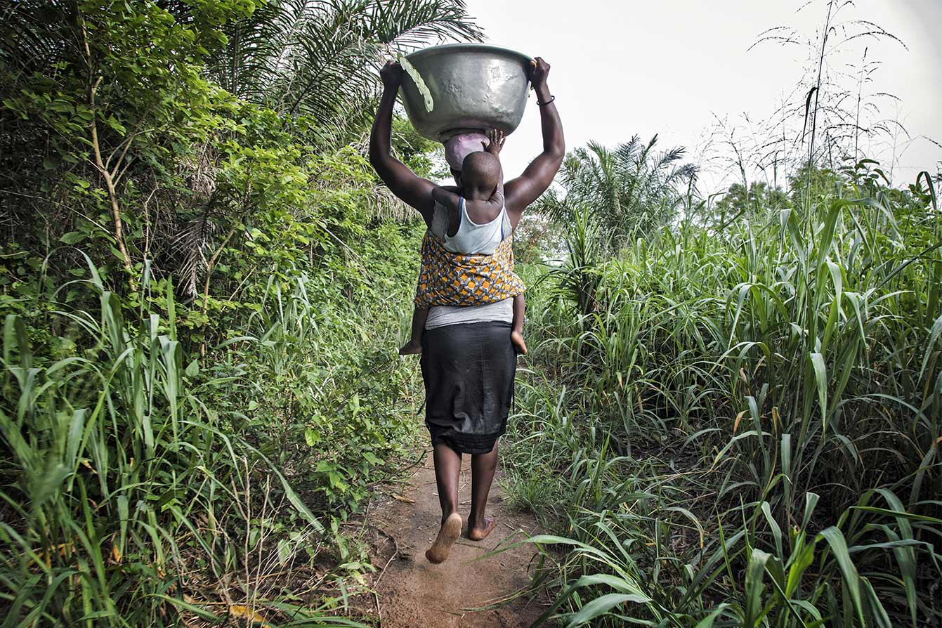 Donna porta una bacinella d’acqua sulla testa. Reportage fotografico sull’energia in Africa.